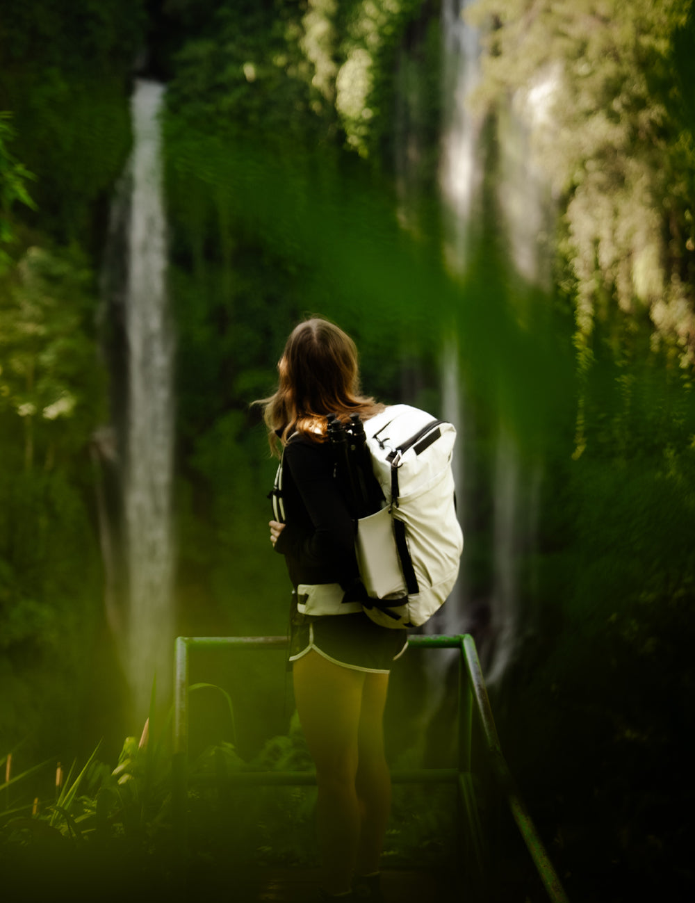 Woman in lush outdoor scene wearing a white backpack