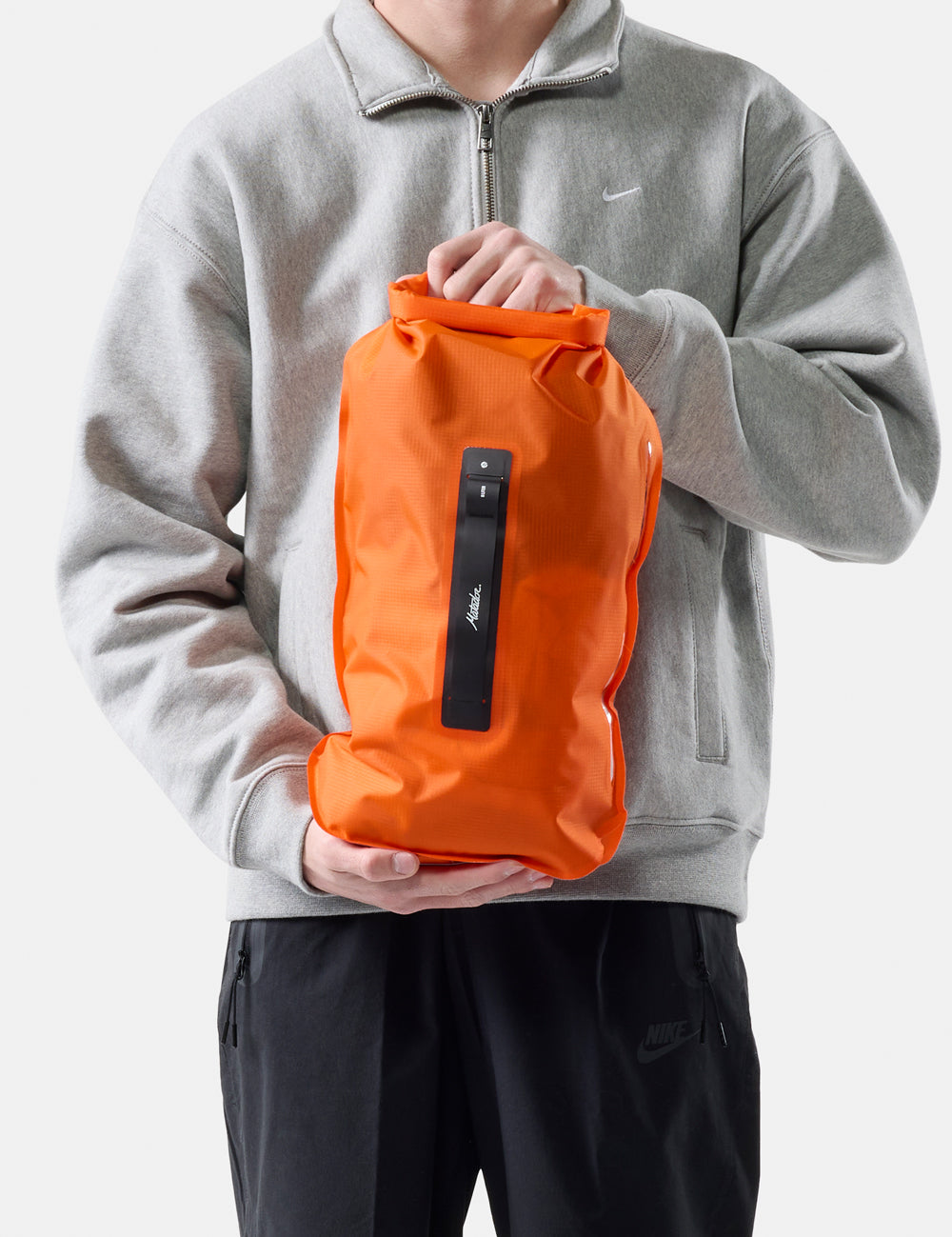 Person holding an orange dry bag with a white background