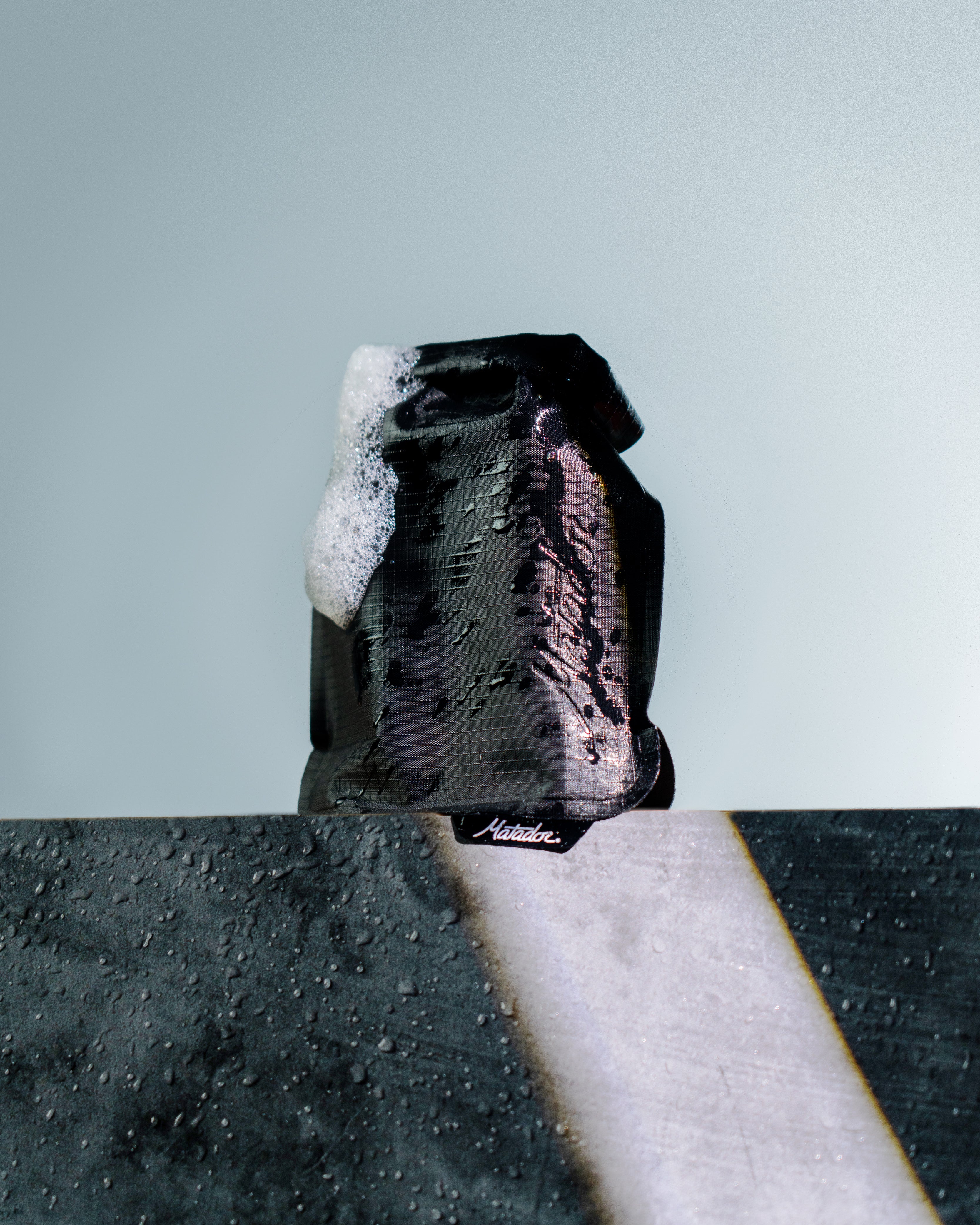 Black soap bar with a white bar of soap on top against a light blue background