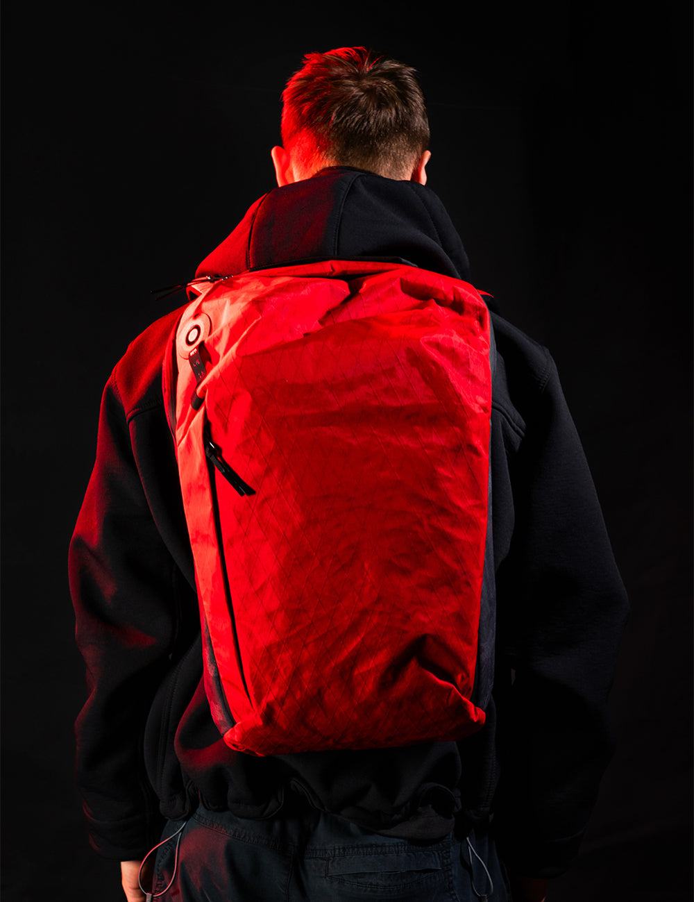 Person wearing a red backpack with a black background