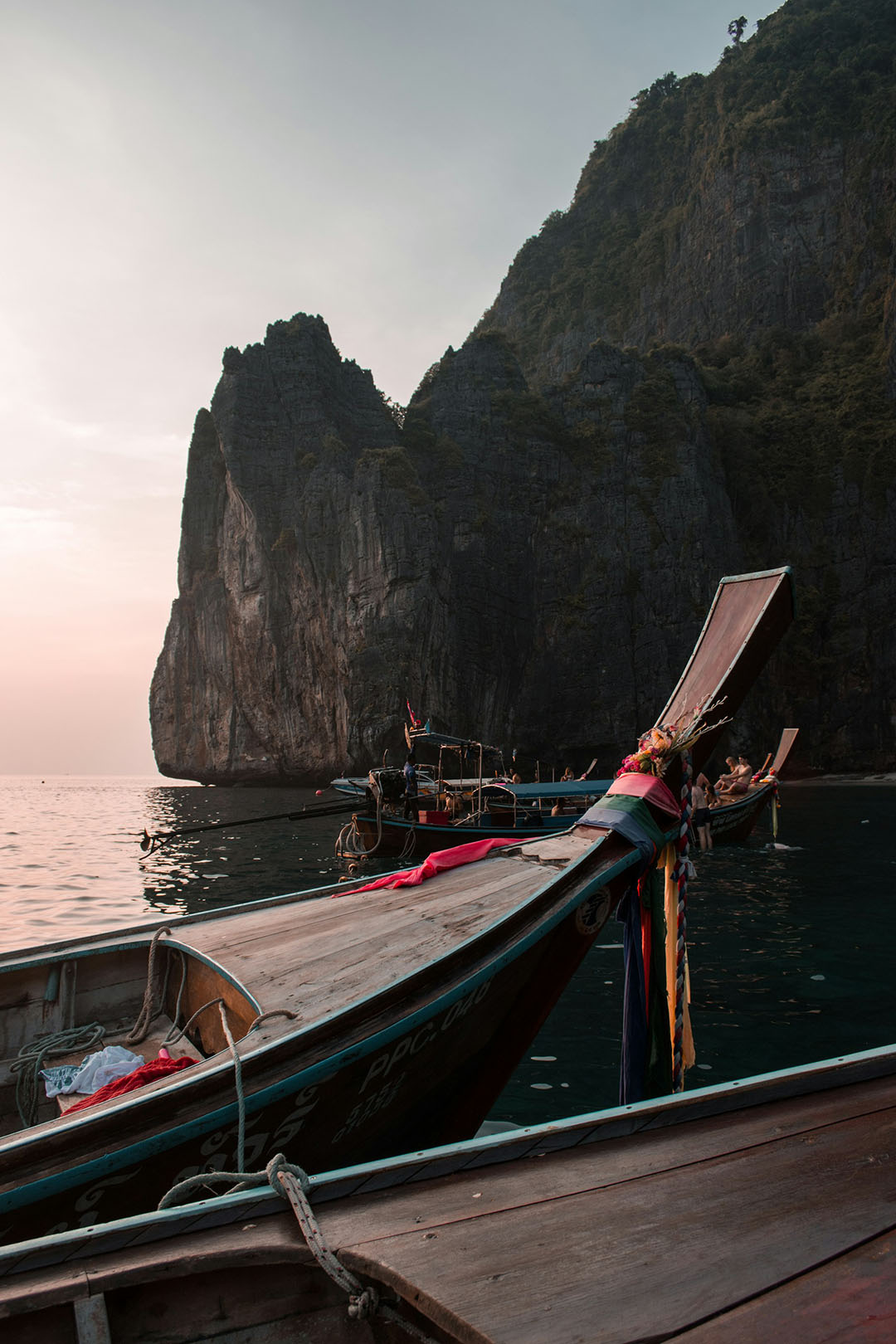 thailand wooden boat in the water at sunset iwth rocky formations in the background