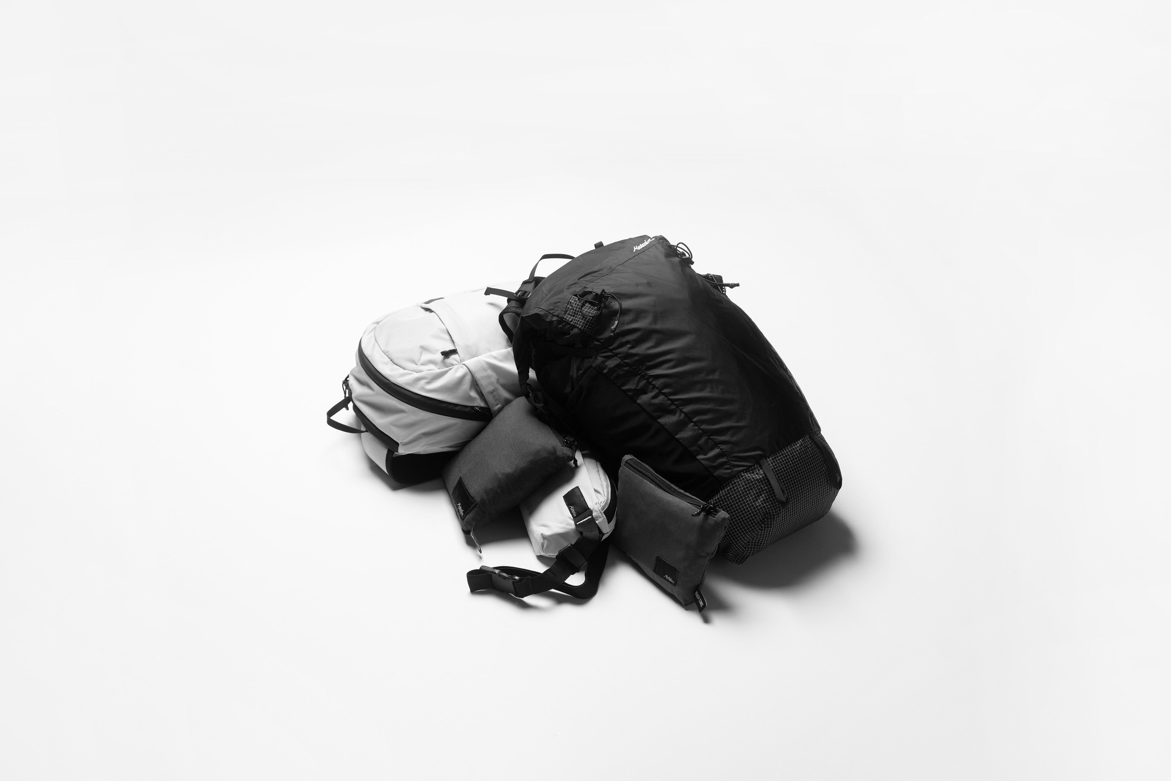 black and white packable backpacks and bags in a pile on a white background