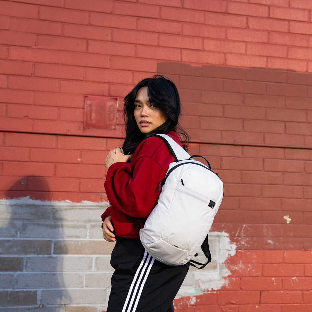person standing by a brick wall wearing a white packable backpack