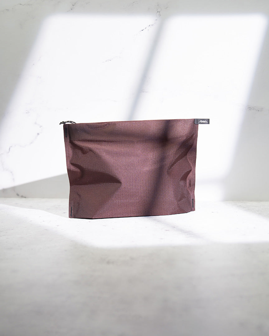 Garnet FlatPak zipper toiletry case standing upright with a marble backdrop