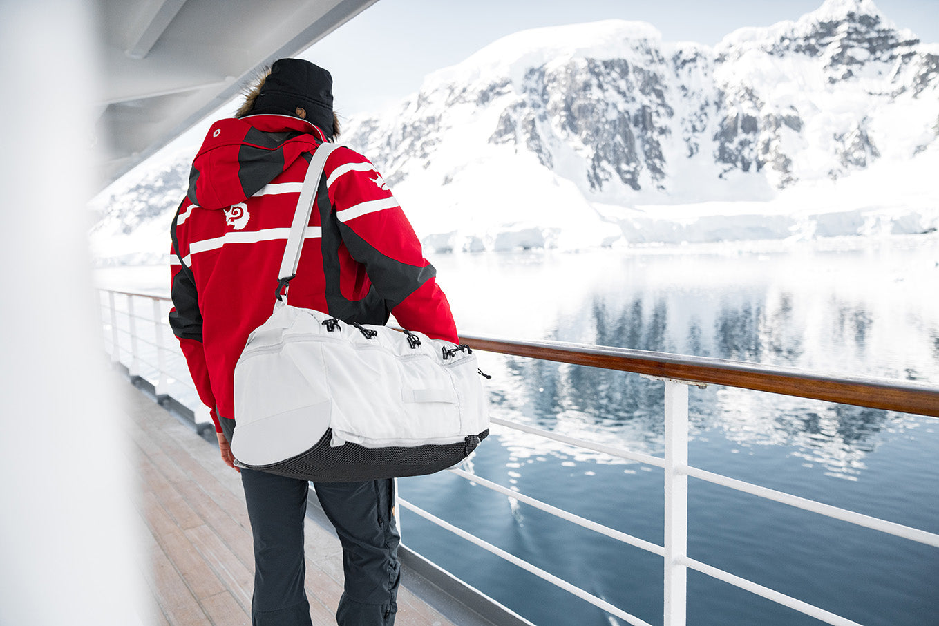 person on a cruise ship with a white duffle bag looking at the snow
