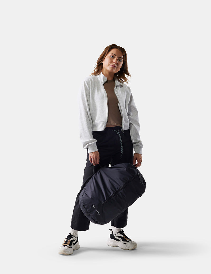 Woman holding a black travel laundry bag against a white background