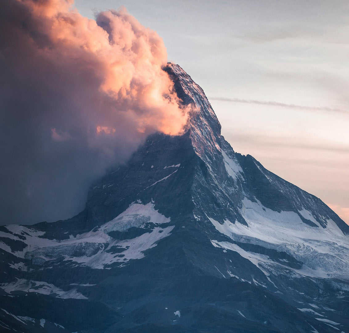 a mountain peak in the clouds at sunrise