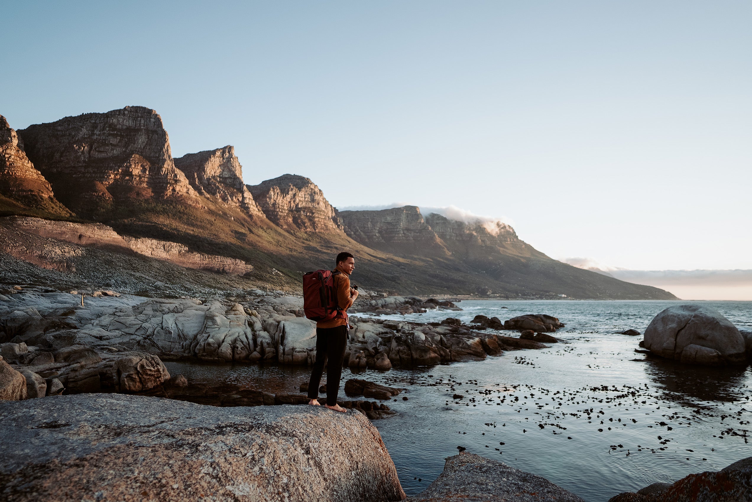 person standing on the edge of a cliff looking at the views while wearing a durable backpack