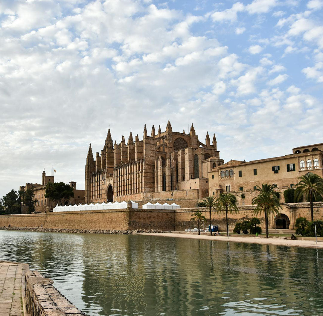 Large cathedral with a moat in front on a partly cloudy day
