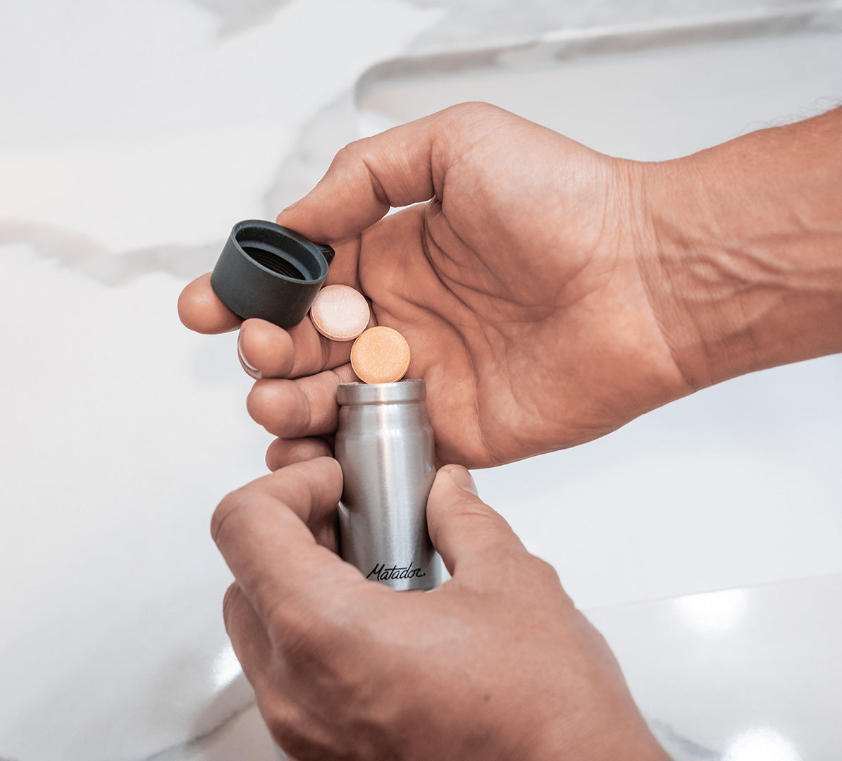 Hands putting medicine tablets in an aluminum pill canister