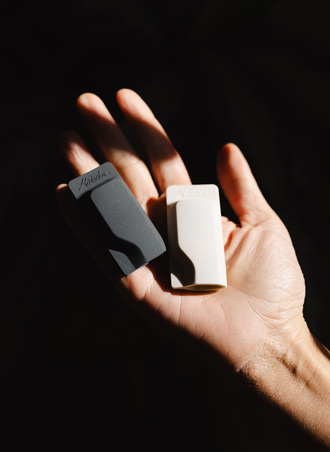 white and black toothbrush caps being held in a hand 